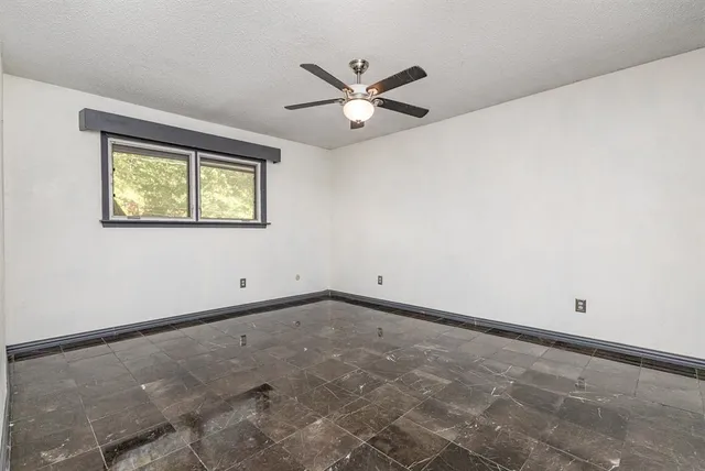 an empty room with a window and a ceiling fan
