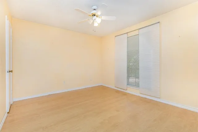 an empty room with a chandelier fan and windows