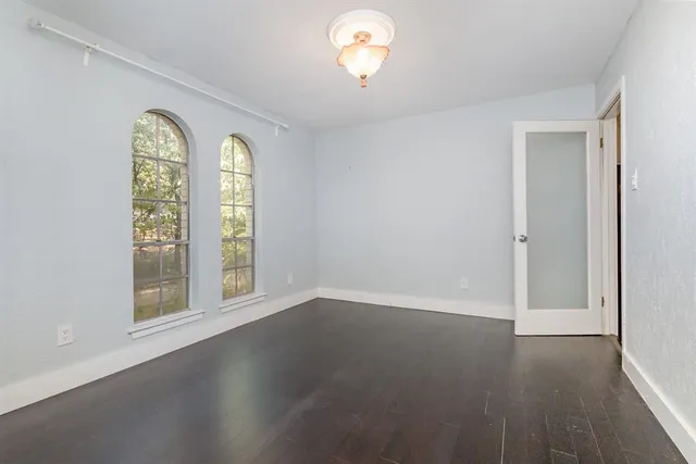 an empty room with windows and wooden floor