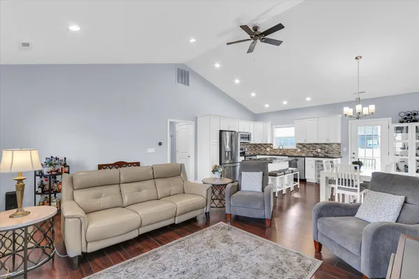 a living room with furniture kitchen view and a chandelier