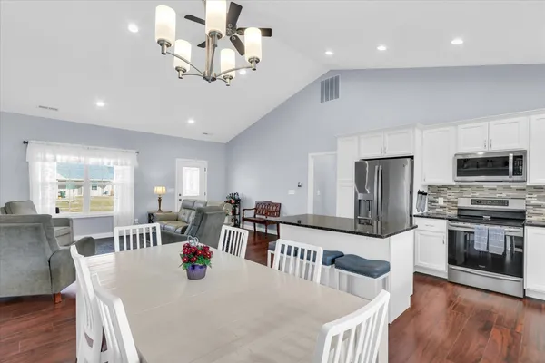 a kitchen with stainless steel appliances granite countertop a kitchen island hardwood floor and a dining table