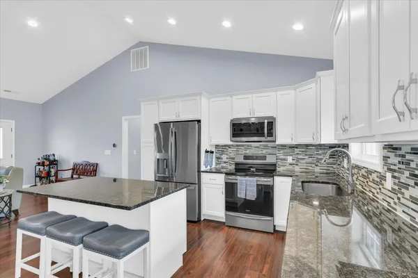 a kitchen with stainless steel appliances a stove a sink a microwave a refrigerator and cabinets