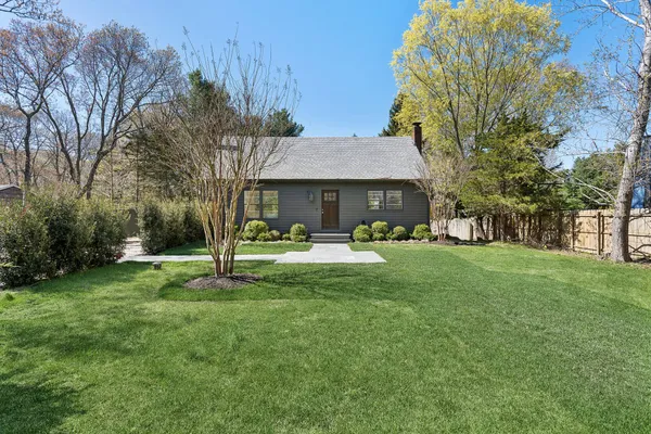 a front view of a house with garden and a tree