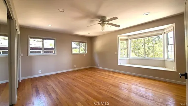 a view of an empty room with a window and wooden floor