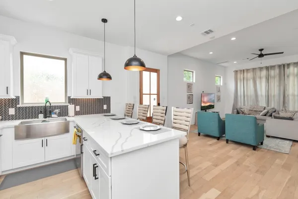 a kitchen that has a sink a counter top space and living room view
