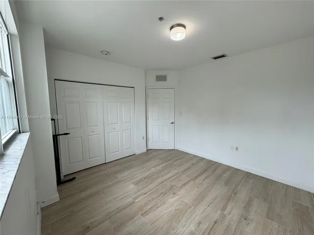 a view of empty room with wooden floor and window