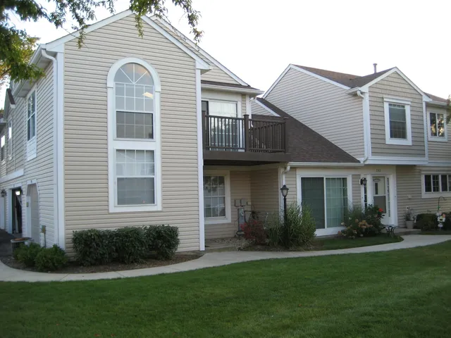 a view of a white house next to a yard with plants
