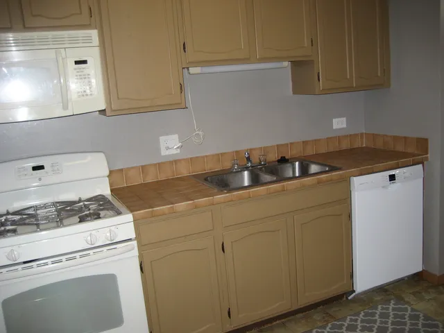 a kitchen with granite countertop white cabinets and white appliances
