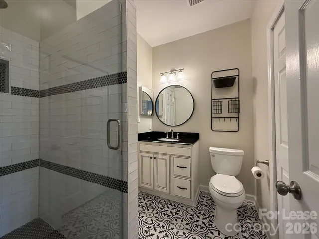 a bathroom with a toilet a sink a mirror and shower