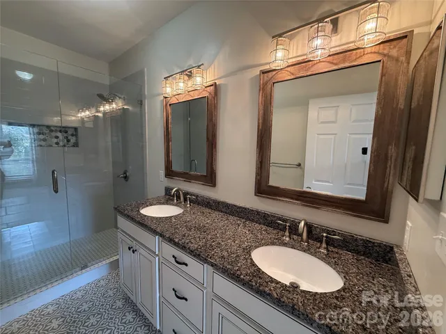 a bathroom with a granite countertop double vanity sink and mirror
