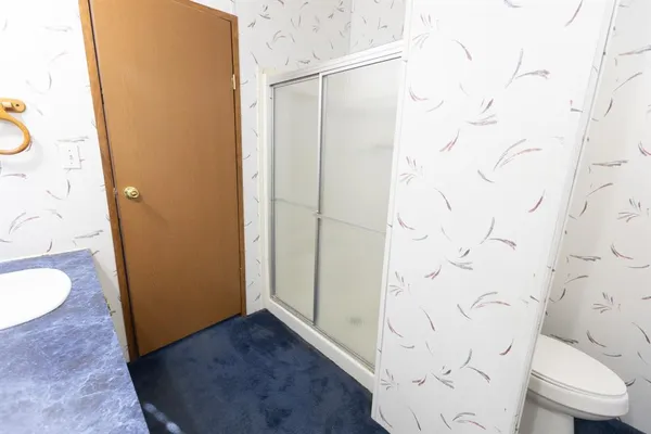 a bathroom with a granite countertop shower and a toilet