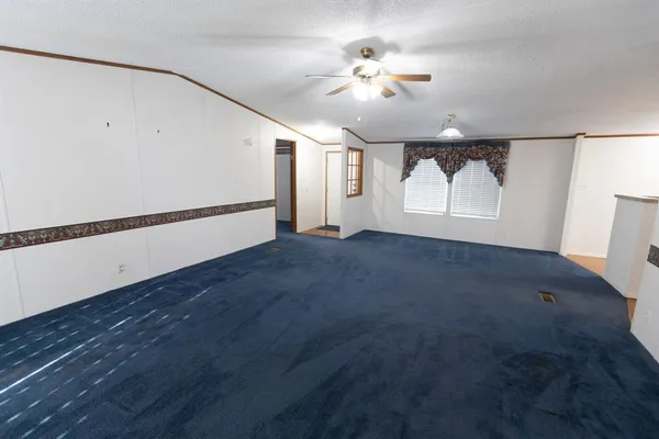 an empty room with windows and chandelier fan