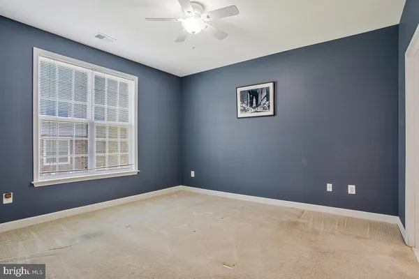 an empty room with a fan & a window