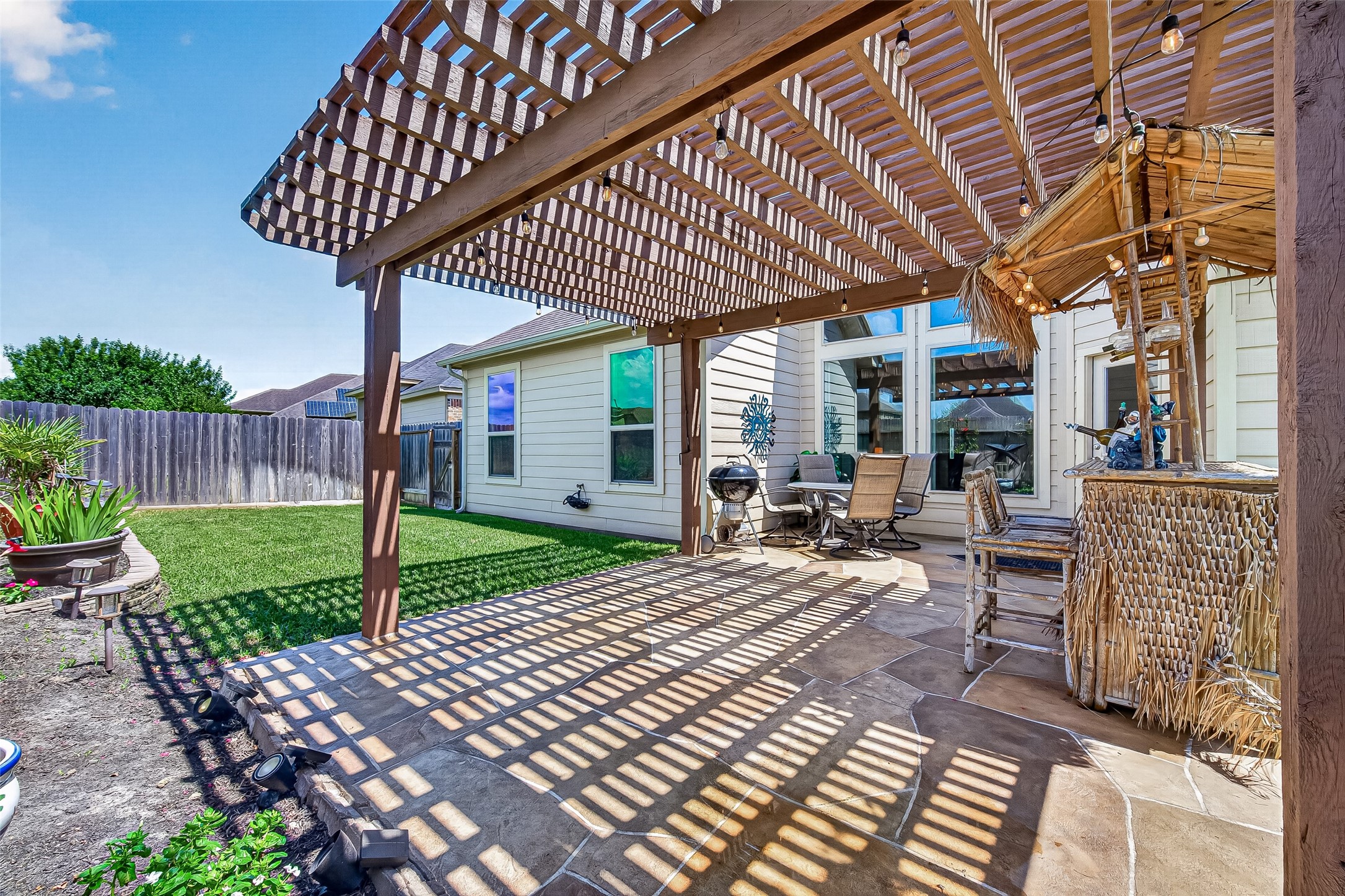 4910 Culver Lane Rosenberg, TX 77471 - Photo 44 of 50 This photo showcases a spacious backyard patio with a wooden pergola, LEAVING PLENTY OF AIR FLOW TO KEEP YOU COOL! Perfect for entertaining. The well-maintained lawn and privacy fence complete the inviting outdoor space.