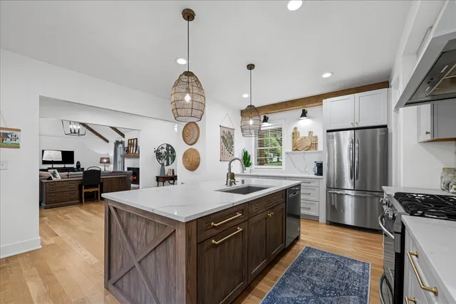 a kitchen with granite countertop a stove a sink dishwasher a dining table and chairs with wooden floor