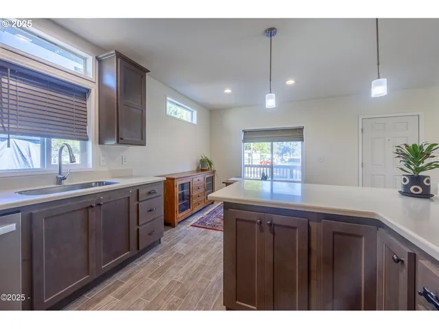 a kitchen with kitchen island granite countertop a sink window and wooden cabinets