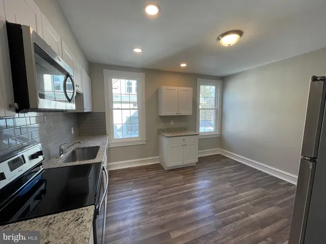 a kitchen with granite countertop a stove a sink and a refrigerator