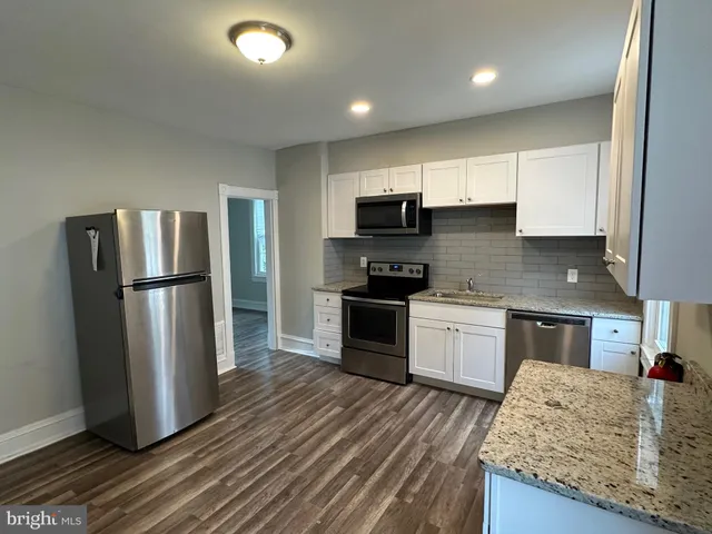 a kitchen with stainless steel appliances granite countertop a refrigerator a stove top oven a sink and dishwasher