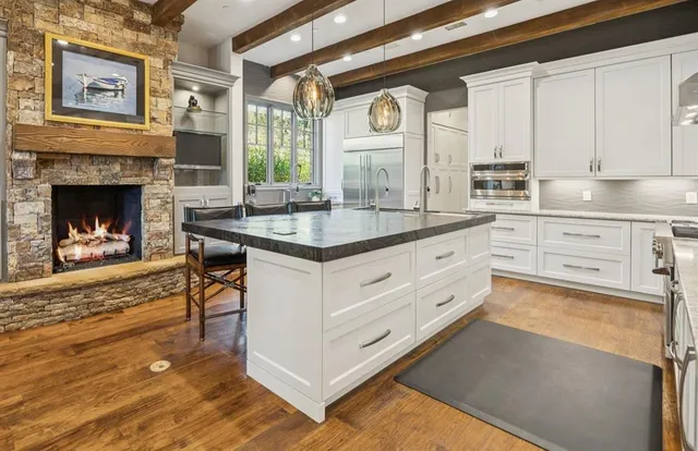 a kitchen with granite countertop a stove a sink and white cabinets with wooden floor