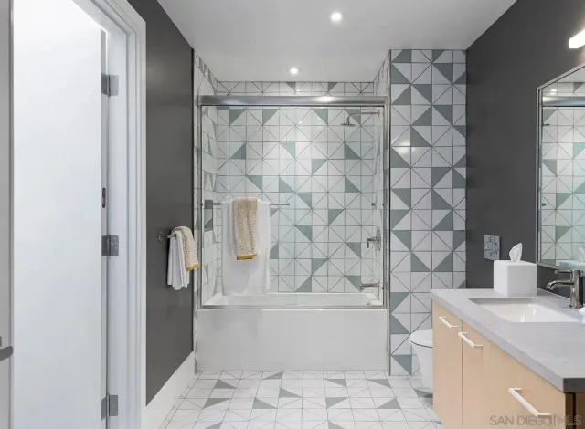 a bathroom with a granite countertop bathtub shower sink and toilet