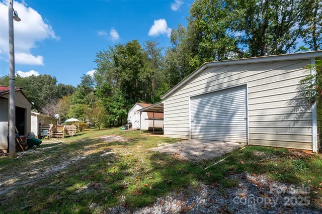 a backyard of a house with plants and large tree