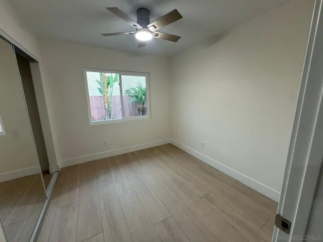 a view of an empty room with a window and wooden floor