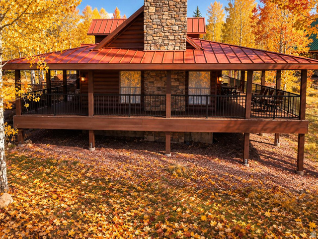 2031 South Quakie Road Koosharem, UT 84744 - Photo 2 of 33 Expansive covered porch with a dark wood railing, stone facade accents, wood siding, and a red metal roof