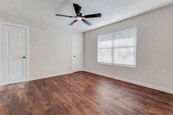 a view of empty room with wooden floor and fan