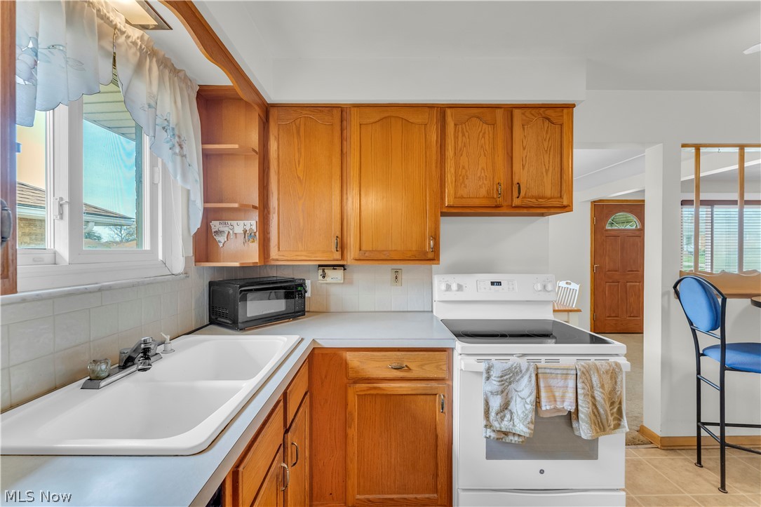 3023 Norris Avenue Cleveland, OH 44134 - Photo 15 of 41 Kitchen featuring wood cabinetry, solid surface countertops, white tile backsplash, and a double basin sink