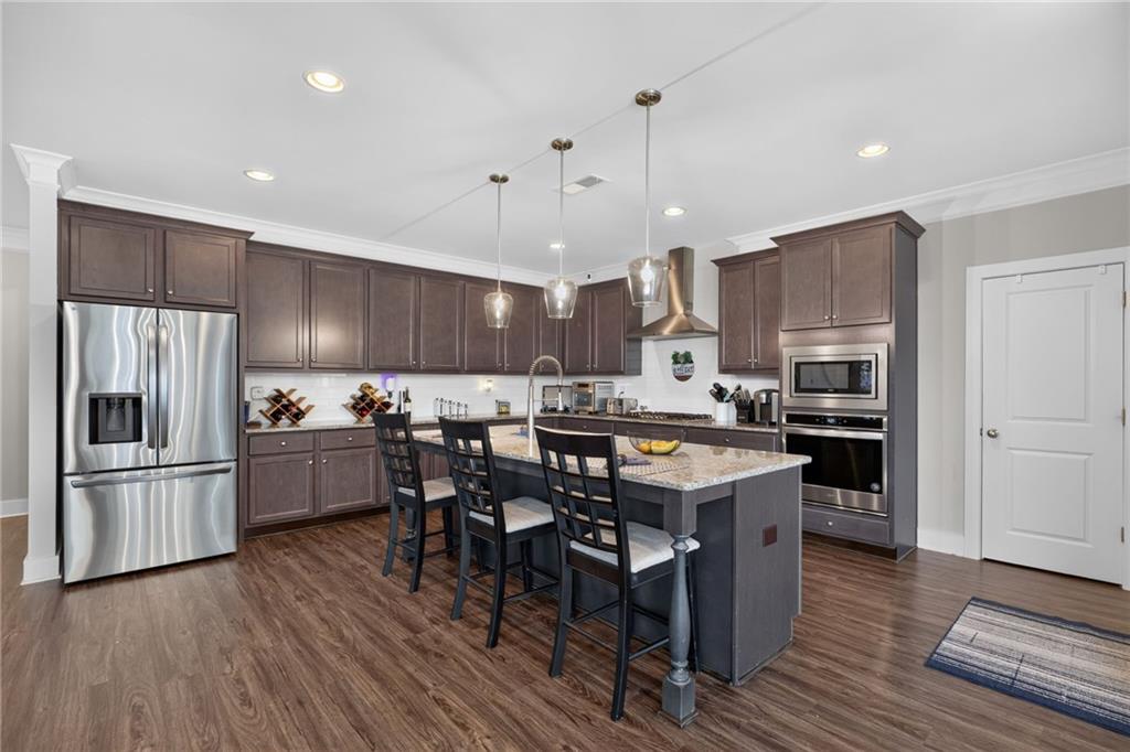 139 Manchester Lane Villa Rica, GA 30180 - Photo 16 of 60 a kitchen with kitchen island a stove a refrigerator and a dining table with wooden floor