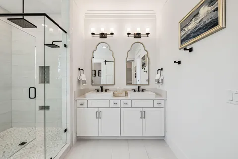 a bathroom with double vanity sink a two mirror a window and a shower