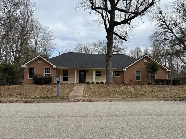 a front view of a house with a yard and large tree