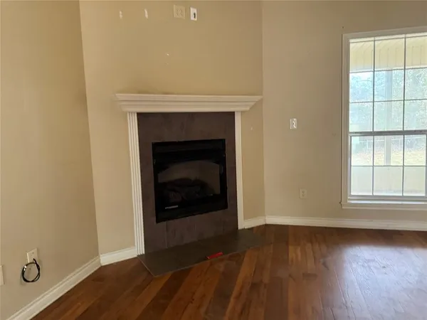 an empty room with wooden floor fireplace and windows