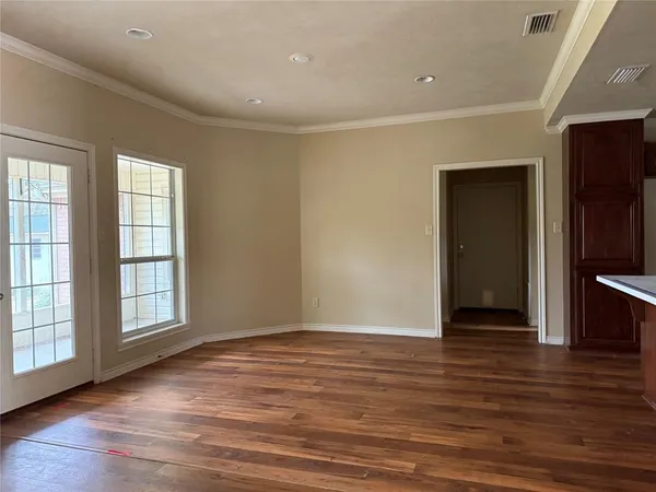 an empty room with wooden floor and windows