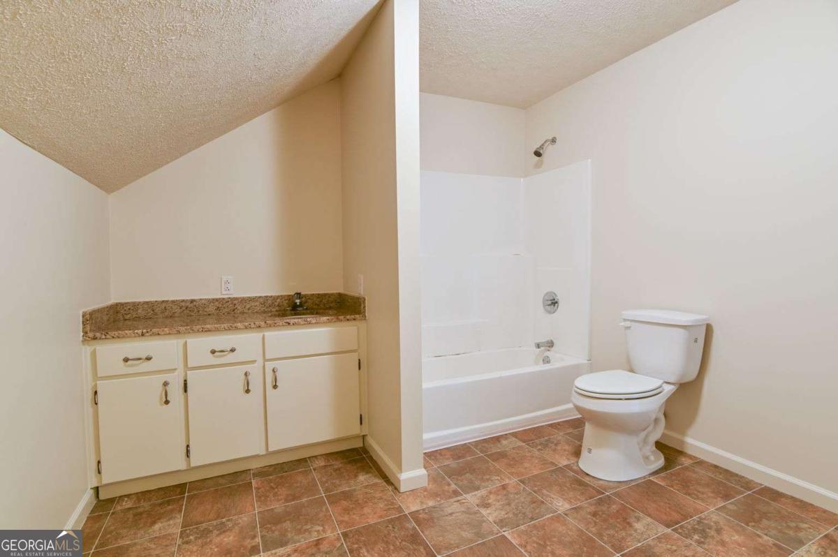 120 Tusten Street Elberton, GA 30635 - Photo 35 of 49 a bathroom with a granite countertop toilet a sink and a bathtub