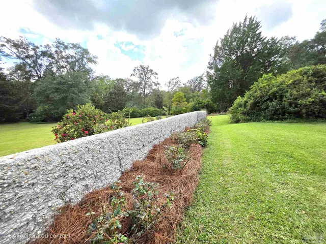 a view of a house with a big yard and large trees