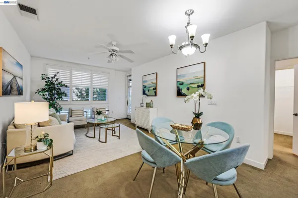a dining room with wooden floor a chandelier a glass table and chairs