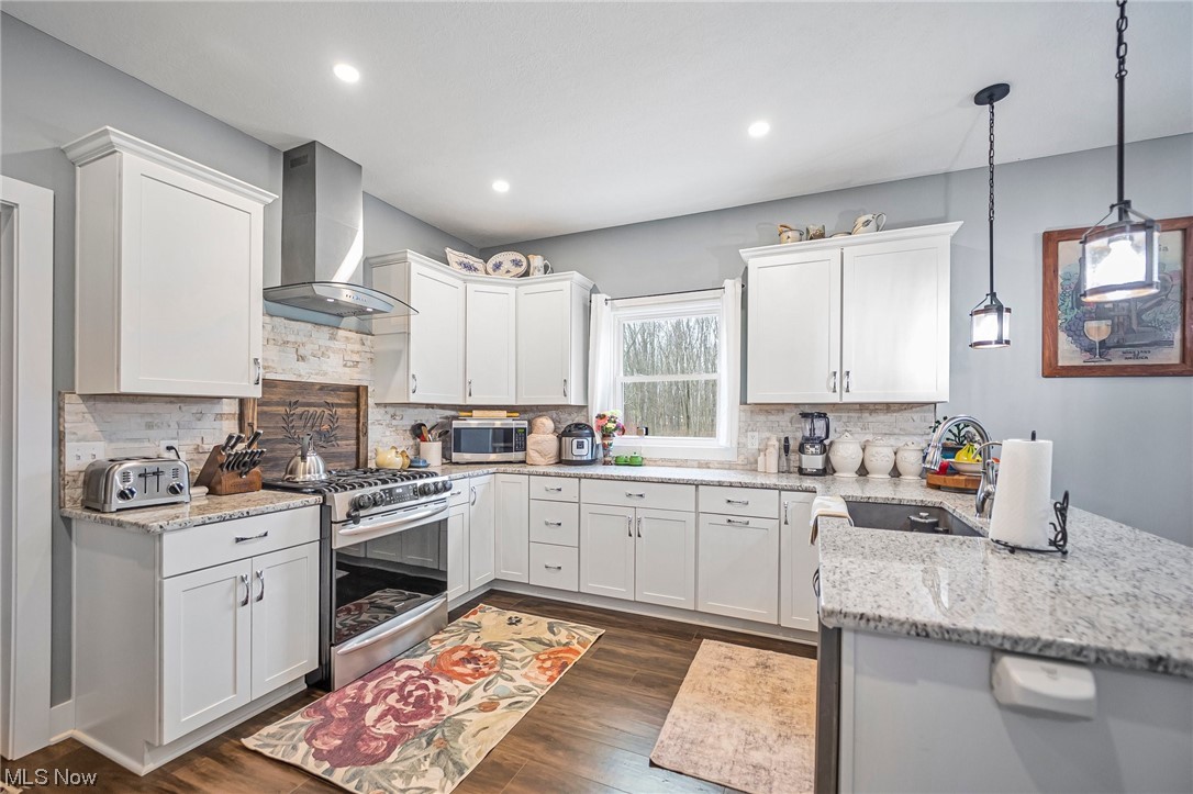 601 Horning Road Atwater, OH 44201 - Photo 2 of 43 Kitchen featuring wall chimney range hood, tasteful backsplash, stainless steel appliances, white cabinetry, and sink