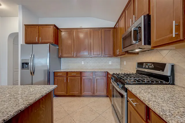 a kitchen with stainless steel appliances granite countertop a stove a sink and a microwave