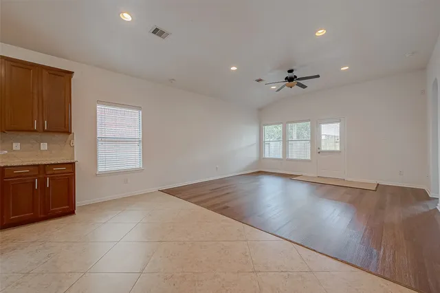 a view of an empty room with a kitchen and a window