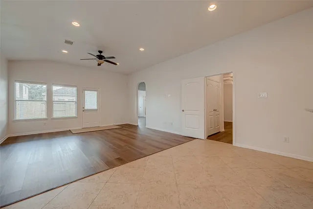 an empty room with wooden floor and windows