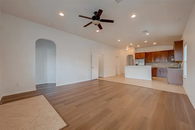 a view of an empty room with kitchen appliances and a ceiling fan