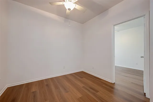 an empty room with wooden floor and fan