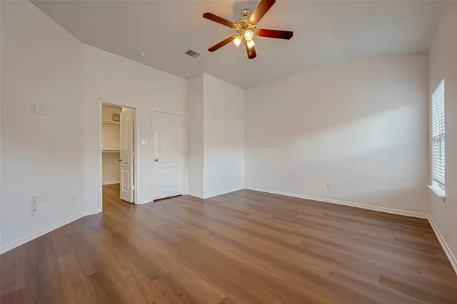 an empty room with wooden floor a ceiling fan and closet