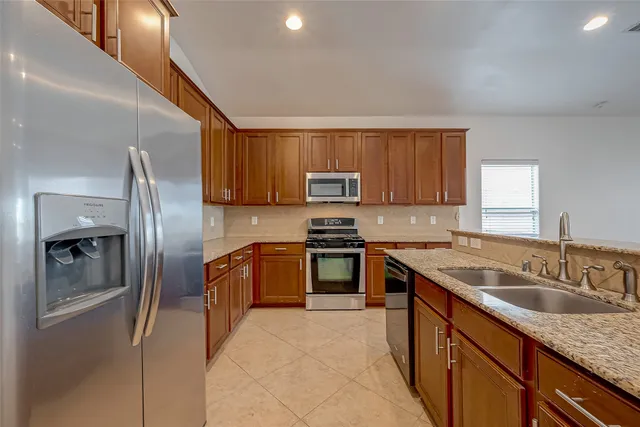 a kitchen with stainless steel appliances granite countertop a sink stove and refrigerator
