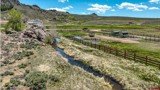 a view of a house with a big yard and large tree