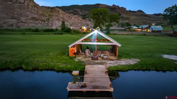 a view of a big yard with lawn chairs potted plants and large tree