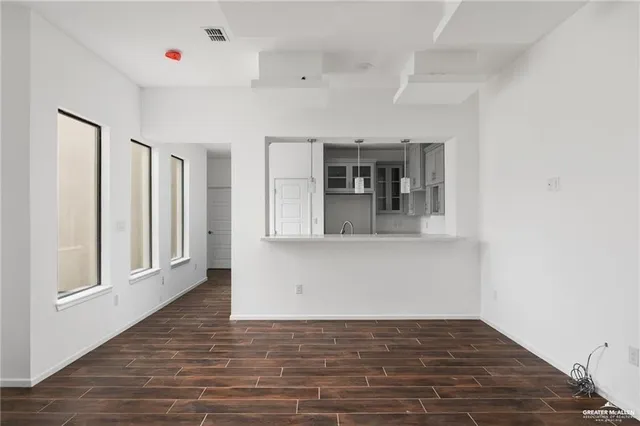 a view of an empty room with window and wooden floor