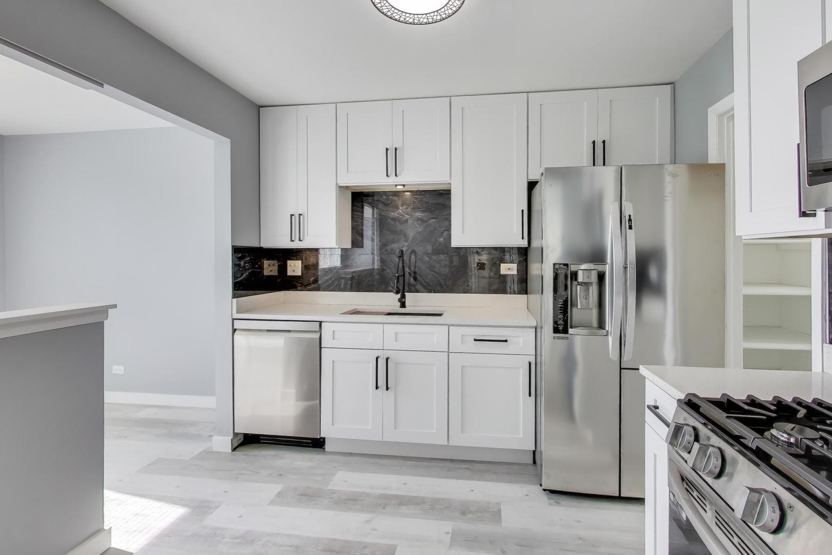 609 Hanover Court, Unit X1 Schaumburg, IL 60194 - Photo 2 of 25 a kitchen with white cabinets and stainless steel appliances