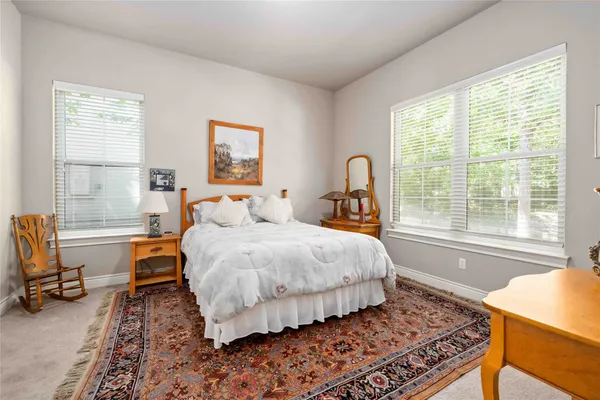 a bedroom with a bed a table and a dresser next to a window